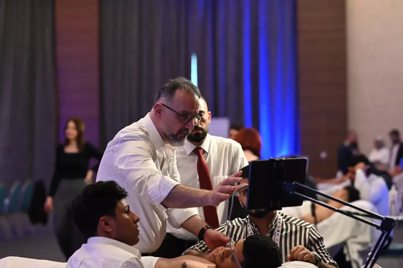 مدرّب يشرح للمشاركين على الجهاز اللوحي في ورشة عملية / A trainer instructing participants on the tablet in a hands-on workshop