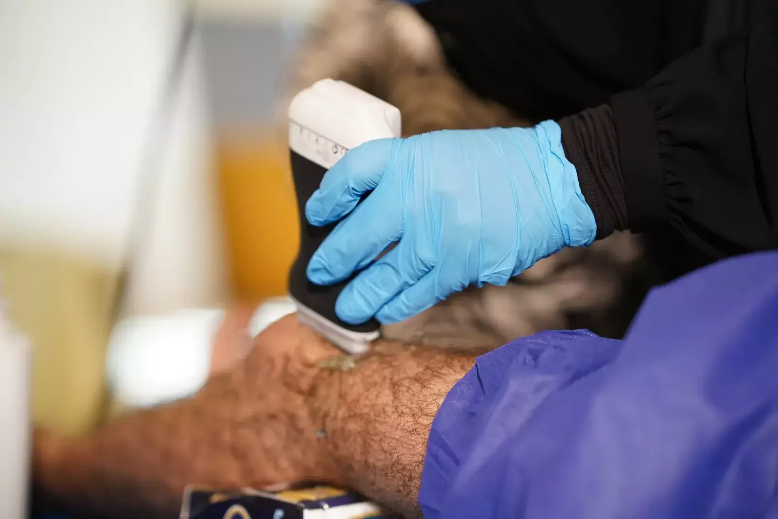 يد بقفاز تثبّت المسبار على الجلد / A gloved hand holding the probe on the skin